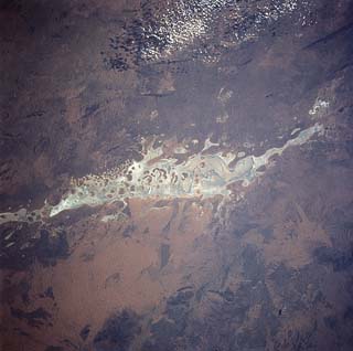 Lake Amadeus ephemeral dry lakebed and Ayers Rock approx. 20 miles to the south in the Simpson Desert of Australia's Northern Territory.